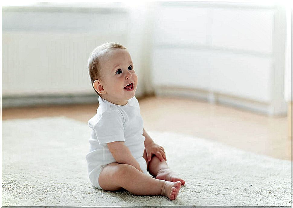 A happy baby sitting on the floor.