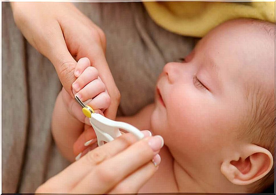 A mother cuts her baby's nails while he sleeps.