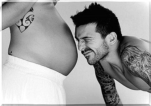 father looking at mom's pregnant belly