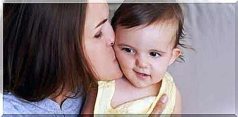 A mother kissing her baby on the cheek.