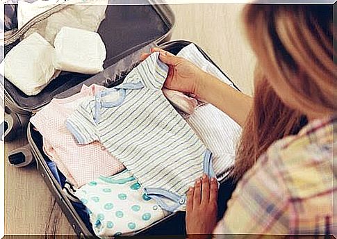 Woman packs baby clothes in suitcase