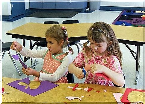 Two children tinkering with scissors and paper.