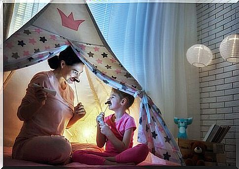 4-year-old child and mother play together in a tent.