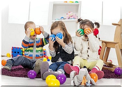 Children holding balls in front of their faces.