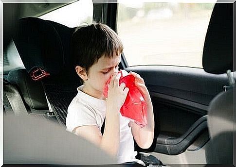 boy in car holds vomit bag in front of mouth