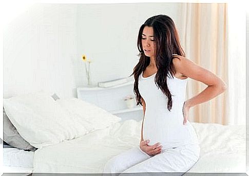 Pregnant woman sitting on the edge of the bed.