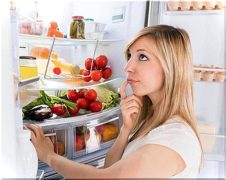 thoughtful woman in front of open refrigerator