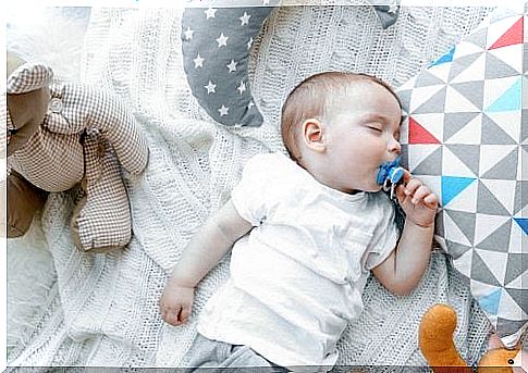 Baby with pacifier in bed.