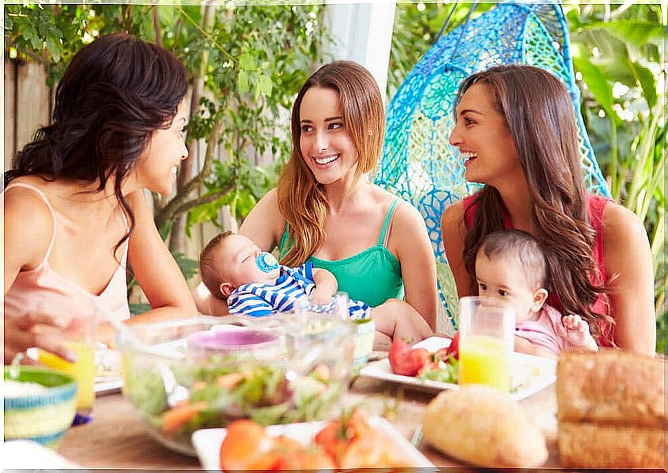 Three women with babies are sitting at a set table