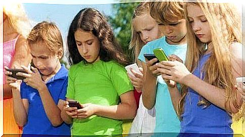 Children stand in line and look at their smartphones