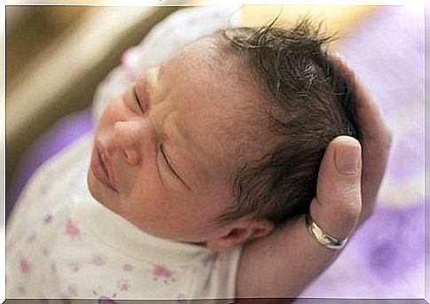 One hand holds the newborn baby's head.