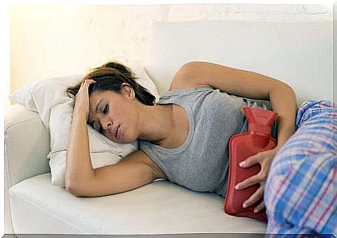 miss your period: woman on sofa with hot water bottle for belly