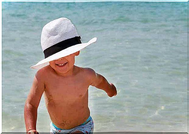 Children with hats running by the water.