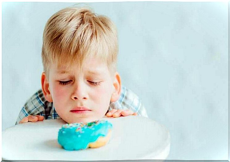 gluten intolerance in children: boy looks sadly at pastries