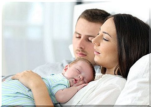 Parents sleep with their baby.