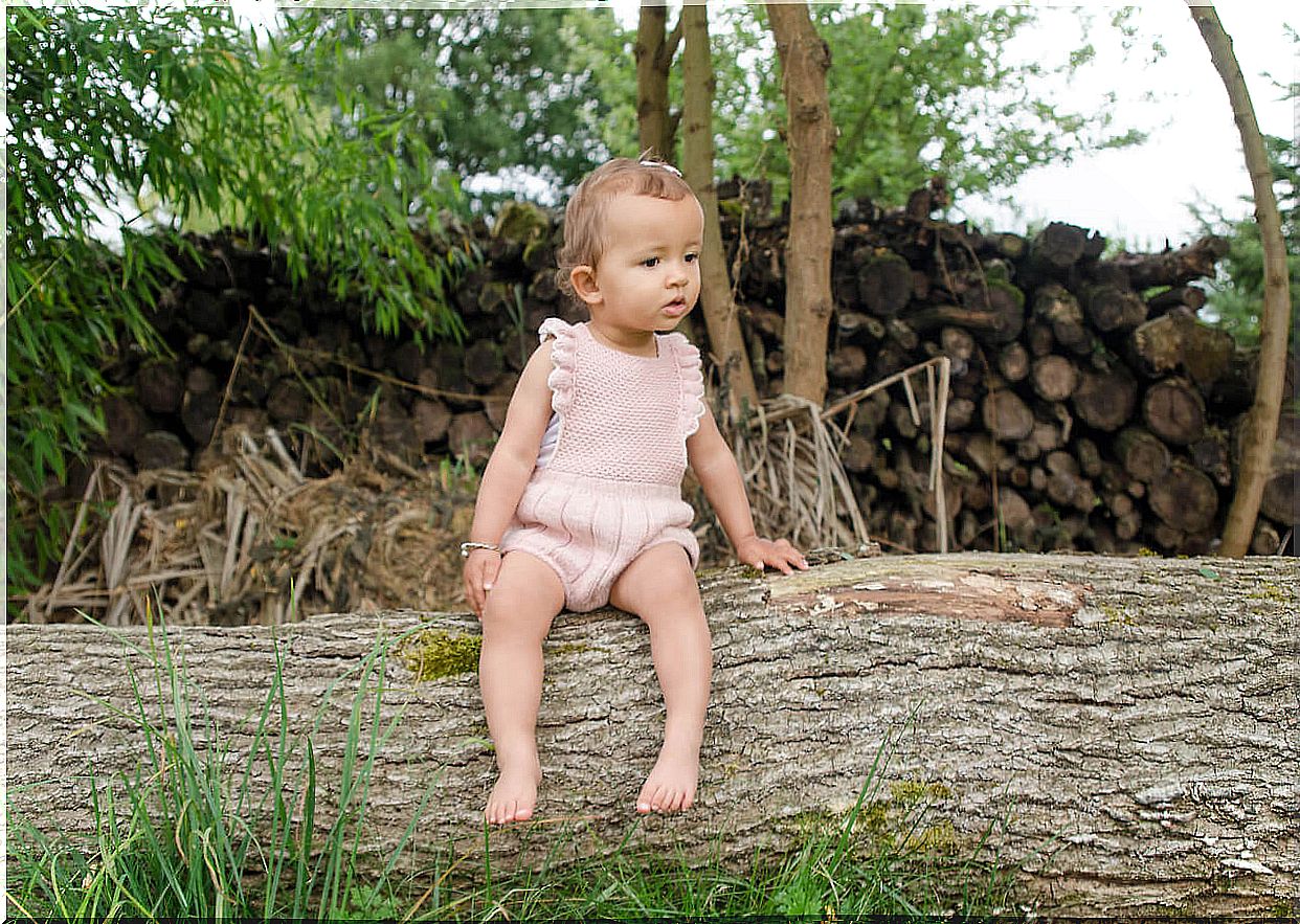 little girl sitting on tree trunk