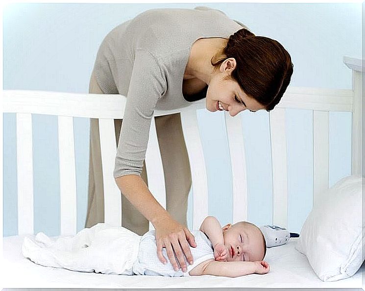 Woman pats baby in crib