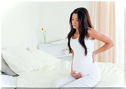 fibroids: woman on bed holding on to belly