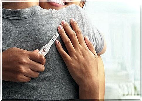 Woman and man hugging each other with a positive pregnancy test