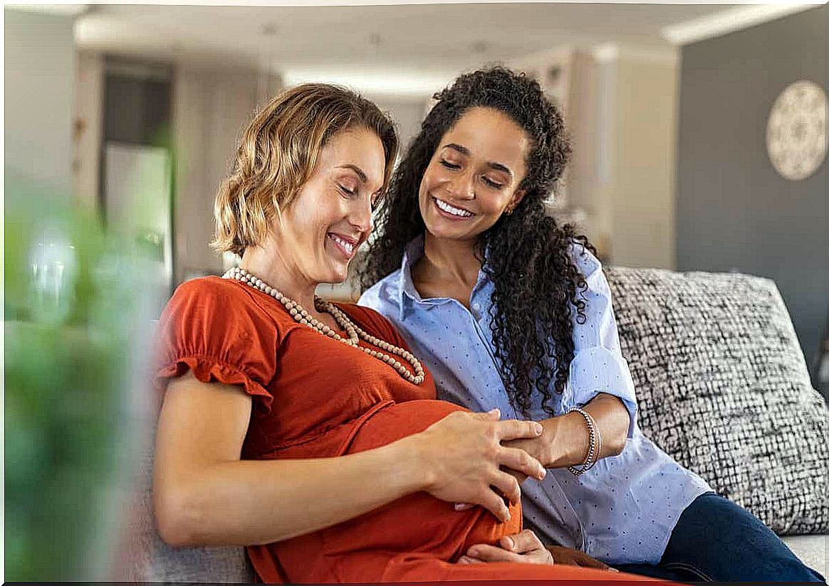 A woman smiling with her pregnant friend.